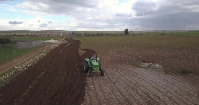 Aerial shot of a tractor in a an agriculture field