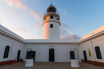 A lighthouse in Menorca illuminated by the sunset
