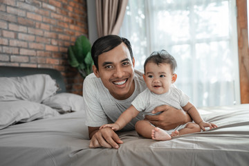 Fototapeta premium father bonding with baby. man playing with his daughter on the bed