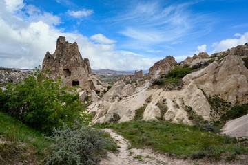 Fototapeta na wymiar The Zelve Open Air Museum in Cappadocia, Turkey, has many sharp limestone mountains in the summer. There are green grass all over the area with blue skies.