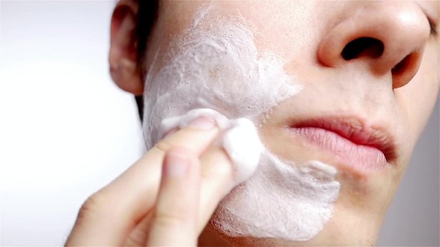 Portrait of male model washing face with facial cleanser wash soap. Beauty man skin care concept.