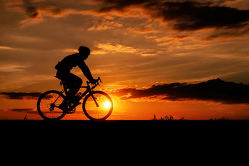 Obraz na płótnie Canvas Silhouette of the cyclist riding a road bike at sunset.
