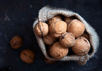 Bag with walnuts on a dark background. Top view