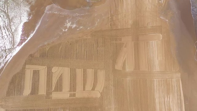 Happy Holiday in Hebrew letters written in Sand on a beach, Aerial view.