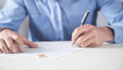 Man with divorce contract and ring on desk. Divorce