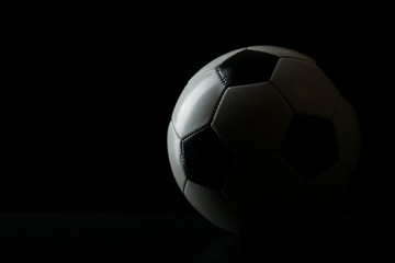 Fototapeta na wymiar football ball with shadow on black background with copy space