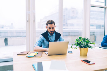 Confident business man with laptop sitting at conference table