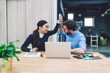 Joyful woman giving high five to bearded man in office