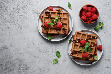 Belgian chocolate waffles decorated with mint and raspberries. Gray background, top view