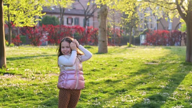 Little girl have fun in the park, sunset sun rays and green grass. The child shows emotions of happiness and positive. Active movements, entertainment. video