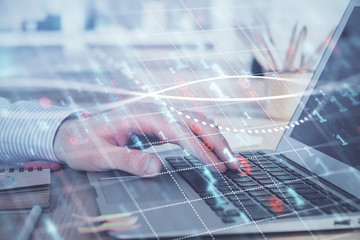 Double exposure of stock market graph with man working on laptop on background. Concept of financial analysis.