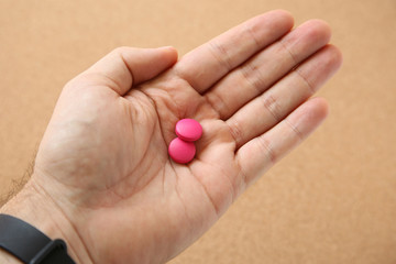 Hand holding pink pills (medical prescription medication). 