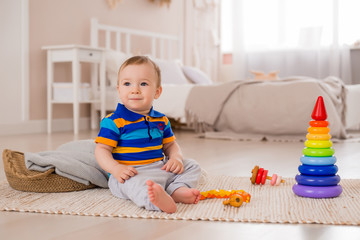Cute kid sitting at home on the floor playing with developing toys. stay at home