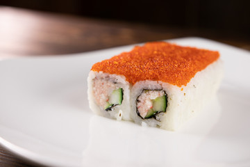 Rolls with avocado, snow crab and red tobiko caviar on a white plate