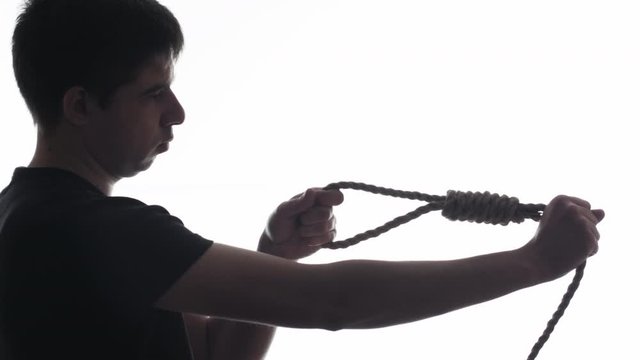 silhouette of man knitting with rope a sea tightening knot on a white isolated background, skill and hobby concept