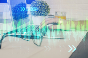 Multi exposure of graph with man typing on computer in office on background. Concept of hard work. Closeup.