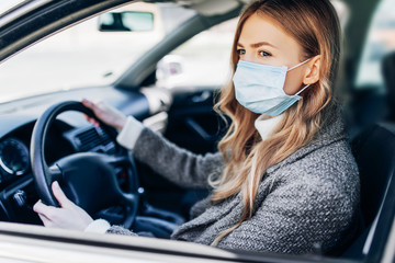 Beautiful young girl in a mask sitting in a car, protective mask against coronavirus, driver on a...