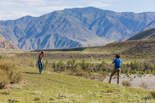 A man photographs the mountains of Altai, next to him is his son