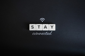 Obraz premium Stay connected concept. Block letters, wifi icon and cursive font on black background. Minimal aesthetics.