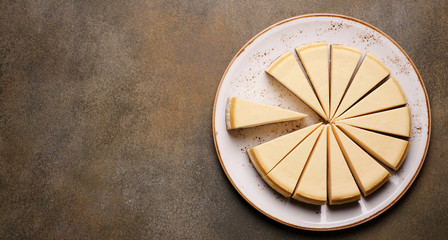 Fototapeta na wymiar Classic vanilla cheesecake cut into pieces. Top view, copy space