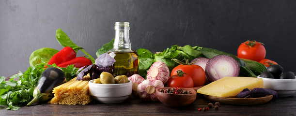 Traditional ingredients Italian cooking. Vegetables, spaghetti, bolognese and tomato sauce, olives, spices. Black stone background