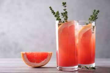Glass of cool grapefruit drink with thyme and ice. Refreshing summer cocktail