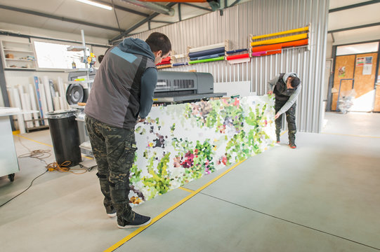 Technicians works in large printing press hall and printshop office