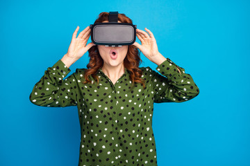 Photo of attractive crazy lady open mouth watch space galaxy planets show in vr box goggles not believe eyes realistic view wear green dotted shirt isolated blue color background