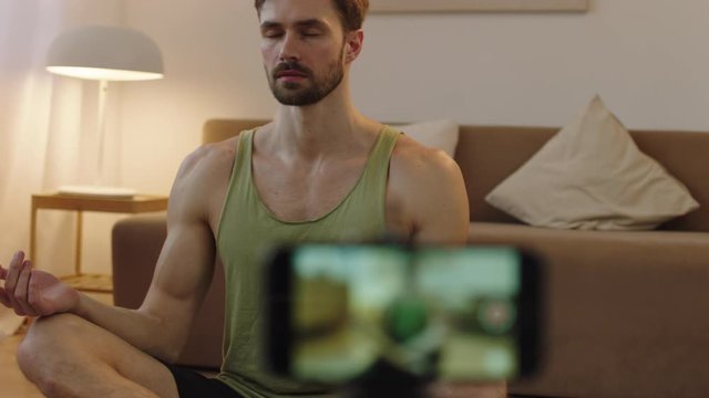 Fit Caucasian male recording a blog or streaming yoga workout from home. Stay home, quarantine life. Shot on ARRI Alexa Mini with Cooke S4 lens