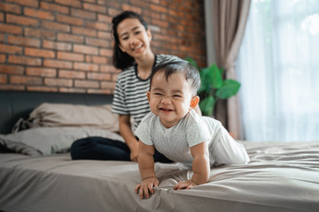 Obraz premium proud mother looking at her baby crawling on the bed