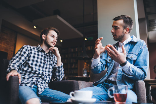 Serious adult males friends talking together in cafe