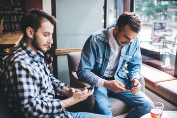 Men in cafe using smartphones