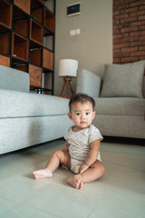 portrait of baby sitting on the floor at home