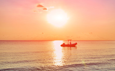 Landscape of paradise tropical island beach, sunrise shot. Beautiful sunrise over the tropical sea. Old fisherman boat at the distance. Tioman Island, Malaysia.