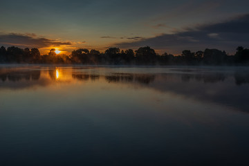 Naklejka premium Bronze sunrise over the lake near the Joseph-Volotsky Monastery. The cloister is located in the village of Teryaevo, Volokolamsk municipal district of the Moscow region.