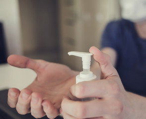 Male hand pressing bottle and pouring alcohol-based sanitize on hands. Disinfection concept. Liquid soap with pumping from bottle.