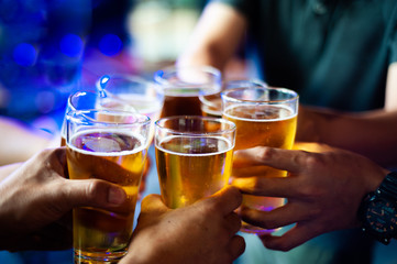 Cheers! Clink glasses. Close-up of a group of people celebrating with beer.