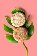 homemade solid shampoo discs on red background close up green natural leaf, example of natural and eco friendly plastic free cosmetic, homemade with herbs