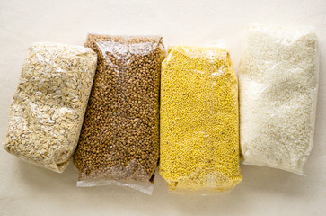 Various raw cereals in plastic packaging on a light background