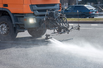 Cleaning machine washes asphalt road surface the city street, close up view.