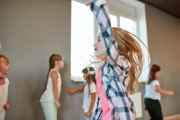 Healthy lifestyle. Portrait of a little happy girl dancing and having fun while having a choreography class. Group of children studying in the dance school