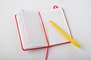 Top view of an open Notepad, pen on a white table background