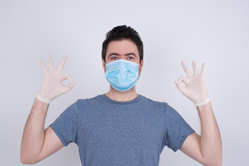 Glad attractive man shows ok sign with both hands as expresses approval, has cheerful expression. Photo of beautiful female has appealing appearance, being optimistic. Standing against gray wall.
