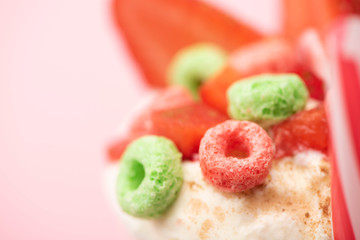 Selective focus of strawberry milkshake with ice cream and colorful candies on pink background
