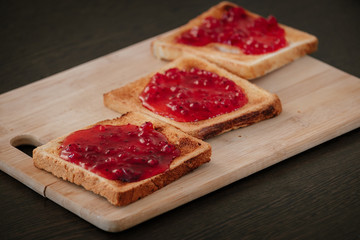 Toast anointed with jam on a wooden board