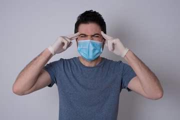Young handsome caucasian man concentrating hard on an idea, with a serious look, thinking with both index fingers pointing to forehead eyes closed.
