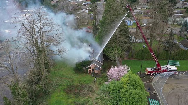 Aerial / drone footage of firefighting efforts under way at a flaming, smoking, burning house in Auburn, King County, Washington