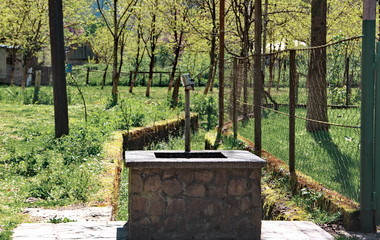 Fototapeta premium Photo of Tap with spring drinking water with a mug on the street, Mirveti village, Georgia