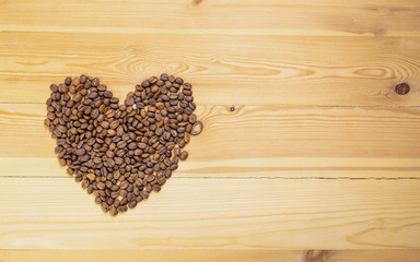 Obraz na płótnie Canvas Roasted coffee beans shaped like hearts on a wooden table