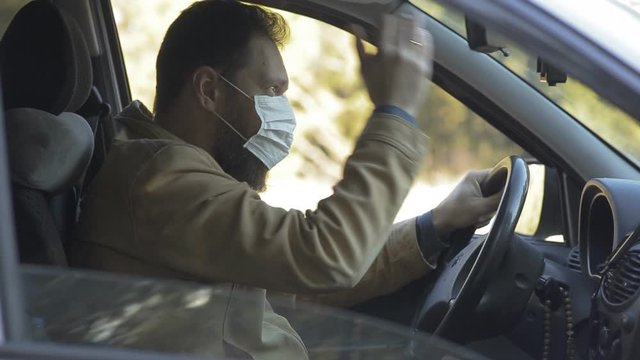 protection from diseases and coronavirus, a man in a medical mask shouts at other drivers from the car window